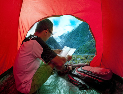 露营男子在帐篷中阅读一本书图片