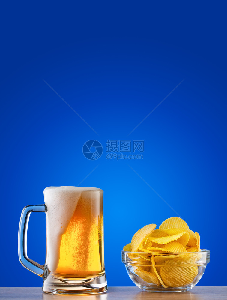 蓝色背景上带泡沫和薯条的淡啤酒杯蓝色背景上带泡沫和薯条的淡啤酒杯金喝液体图片