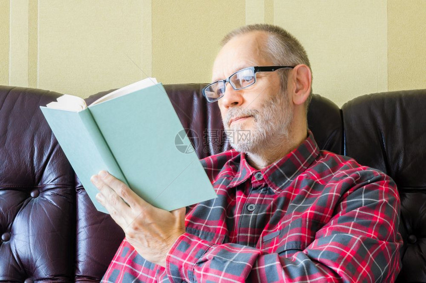 一个长着胡子和眼镜的老人坐在沙发上看书保持58皮卡自然图片