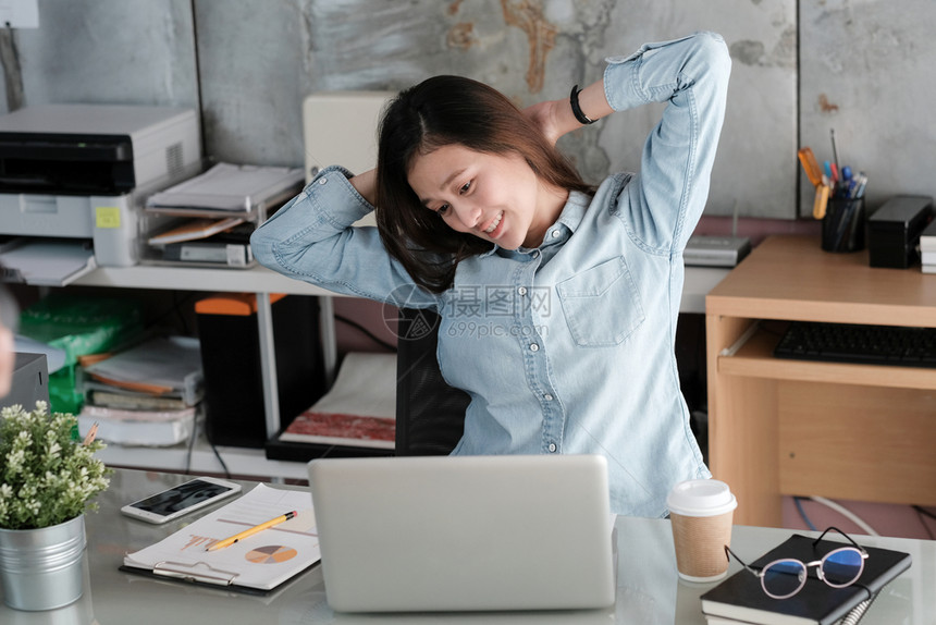 成人亚洲在办公桌上用笔记本电脑工作办公室生活方式商业状况时年轻的青女在从事个人电脑工作时伸展身体以放松力尽管图片