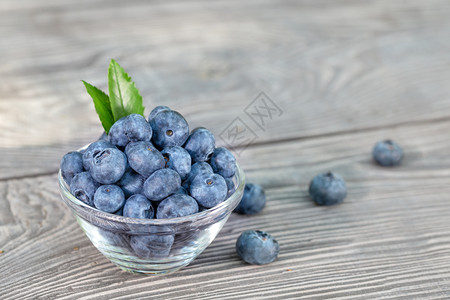 蓝莓放在木桌上的玻璃碗里蓝莓放在木桌上的玻璃碗里黏土叶子蓝色的图片