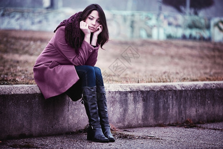 令人沮丧的年轻女正坐在萧条中Gloomy秋天的石柱上多雾路段悲伤公园图片