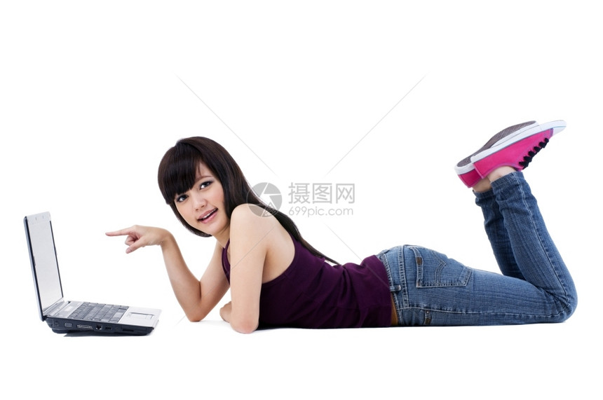 亚洲人指点漂亮的一名美丽年轻女士肖像躺在地板上用白色背景指着她的笔记本电脑图片