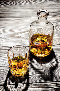 陈年好酒酒精骰子桌木上的玻璃瓶和一杯陈年干邑在木桌上拍摄了玻璃瓶和一杯陈年白兰地背景