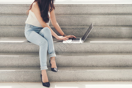 女孩在职的衣服白衬衫蓝色牛仔衣黑长头发使用电脑笔记本坐在楼梯上图片
