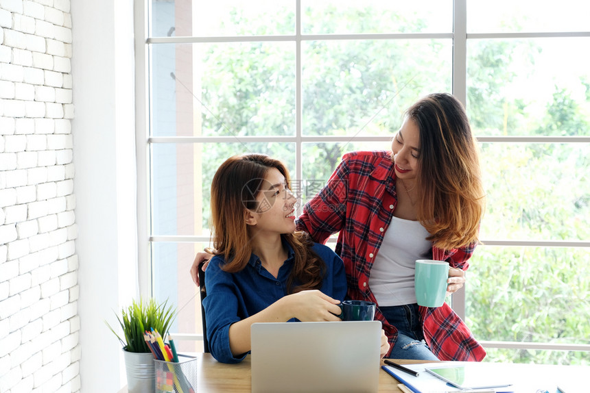 在职的两名年轻女在家庭办公室以快乐的情感在家工作小企业办公室临时生活方式概念从事笔记本电脑工作的年轻青女真实的网络图片