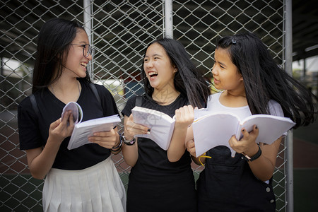 学习友谊健康亚裔青少年持有学校书本在户外欢笑与快乐的情绪图片