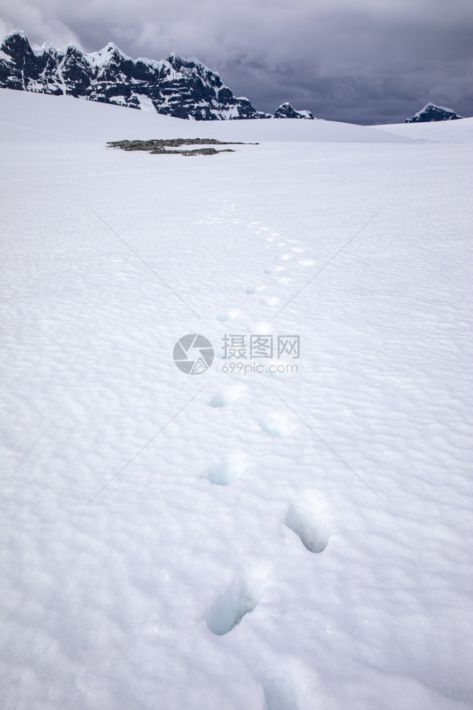 渡船小路通过深雪的足迹穿过宽阔的冰平原到南极山偏僻的图片