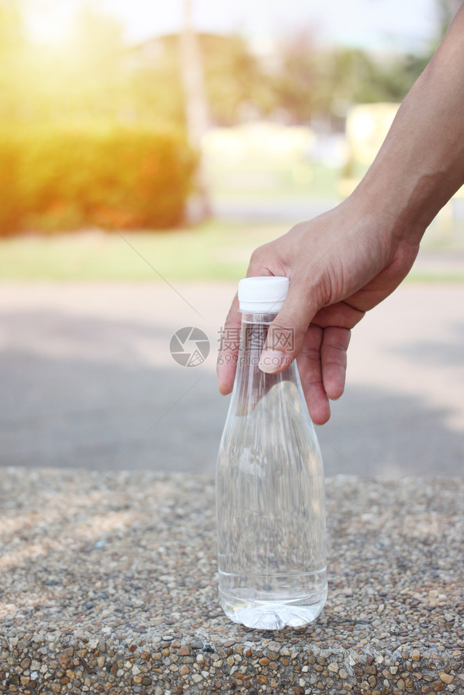 新鲜的一个男人在花园里拿着一瓶饮用水的手复制塑料图片