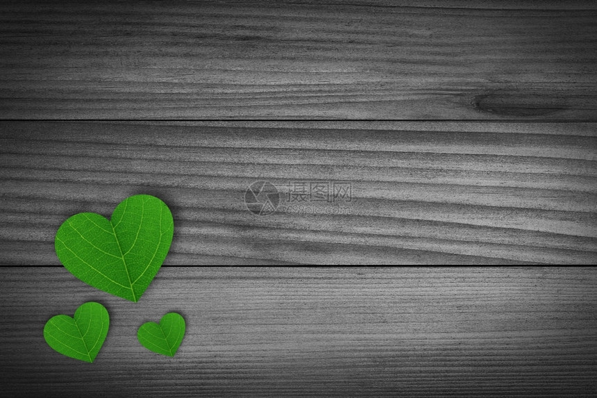 情感概念的一种绿色踏脚石塑造的心脏躺在一块旧木头上图片