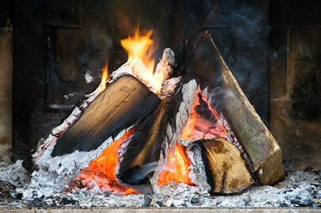 热几个木头燃烧在一小壁炉里周围有灰烟雾和火焰吠经过高清图片