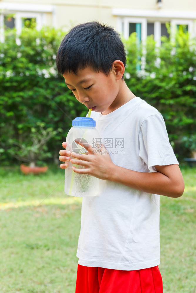 衬衫泰国男孩用稻草喝来自糖瓶的冷水子亚洲人图片