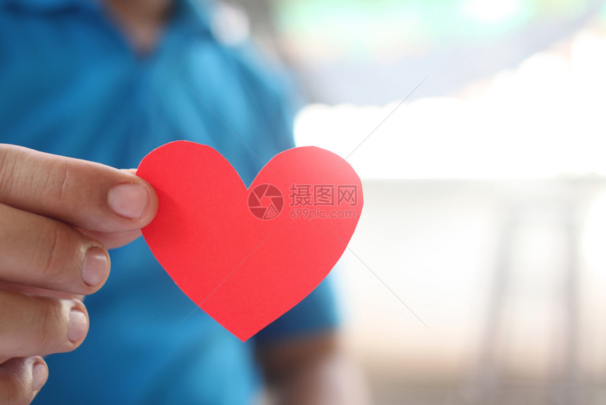 一个男人手里握着红色的心在爱和情人节的概念中一个男人关心礼物快乐的图片