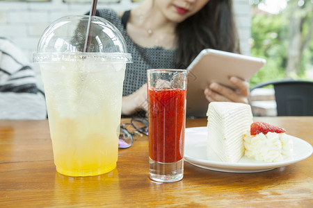 黑纱桌子食物妇女坐在木板上手拿着智能垫子手握着草布便蛋糕准备在桌上吃图片