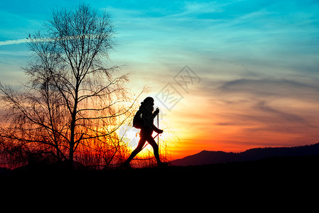 高山户外北欧人走在山上日落时一个女孩的彩色背影天空图片