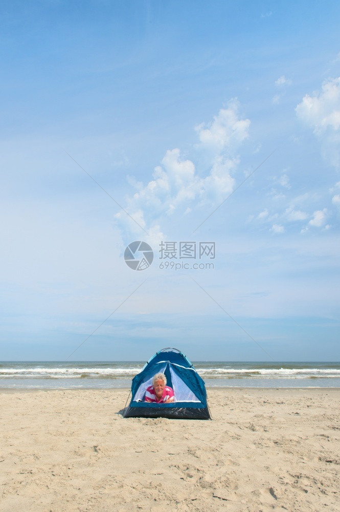 树干水单身的老年男子在海滩的避难所露营图片