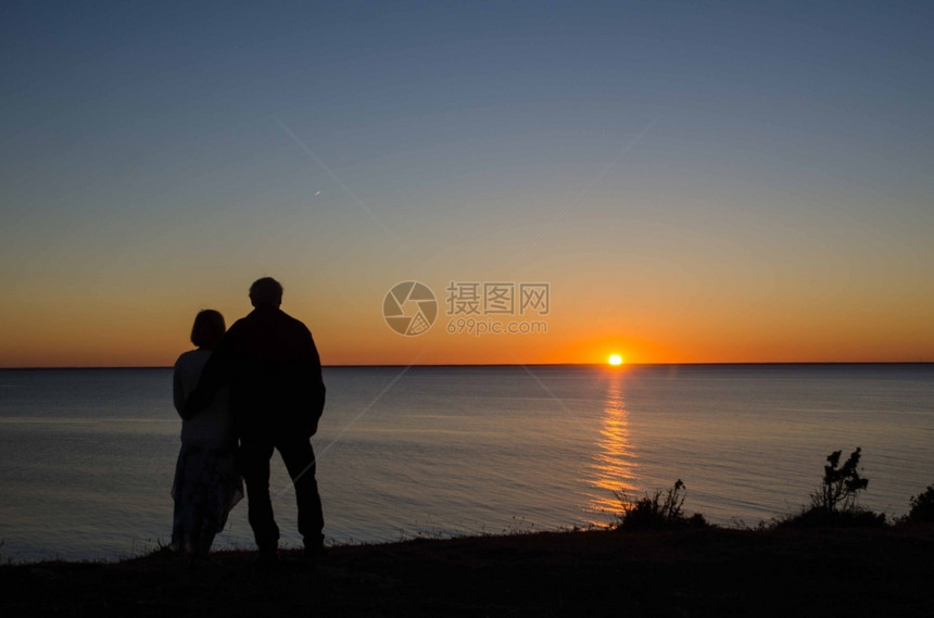 闲暇一对夫妇在海边的地平线看日落天空乐趣图片