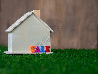在绿草坪上安装木制房屋模型在子上加绿色草坪和多彩的文本销售花园家庭买图片