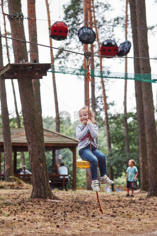 开支绳索快乐的女孩骑在林中绳子公园的拉链上同时度暑假真实的人情况滑动图片