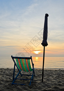 橙海岸浪日出时在泰国差安海滩的多彩沙椅图片