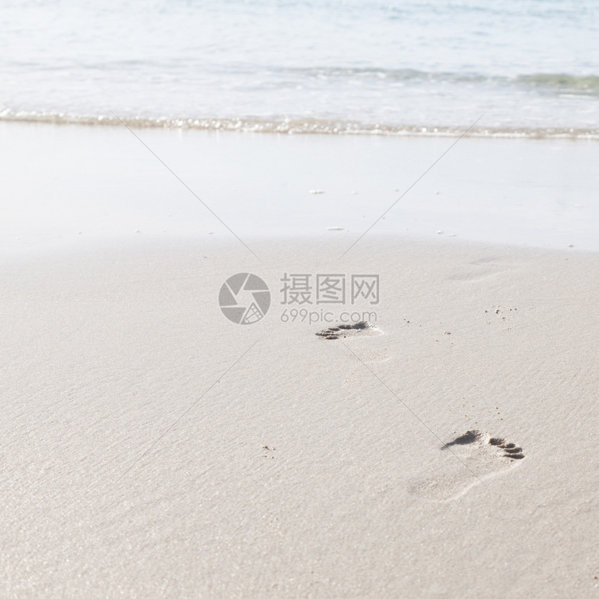 在海边滩上行走的人们脚足迹印在沙滩上的脚浪漫热带小路图片