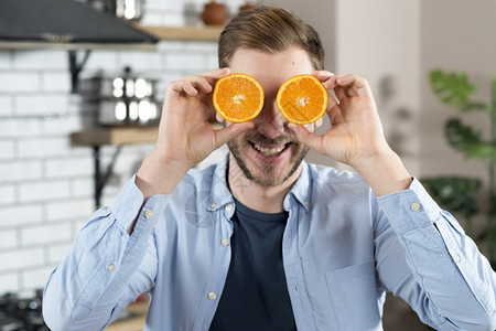 年轻人拿两片橙子来取乐维他命里面吃图片