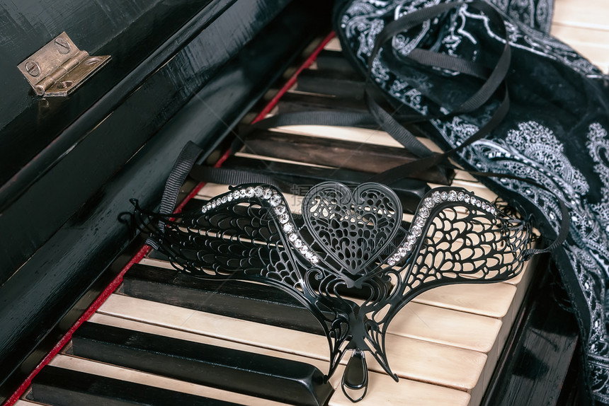 礼物优雅女在钢琴键盘上戴有瑞林石的心脏形状和长年风格背景上的围巾女在胸前戴有瑞林石的心脏形状中双假肢婚礼图片