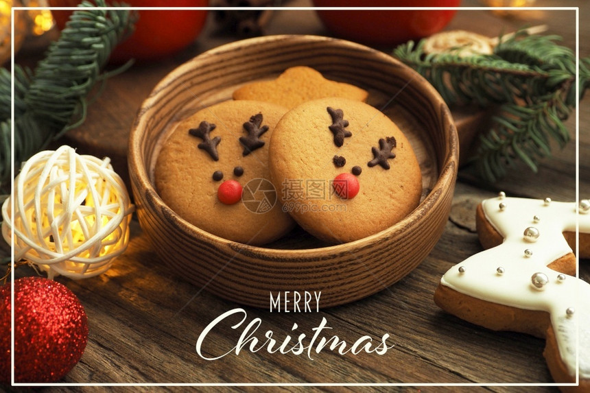 信仰花环圣诞节卡上面刻着圣诞快乐的姜饼干里面有鹿脸园地圣诞树枝和木桌上的蛋图片