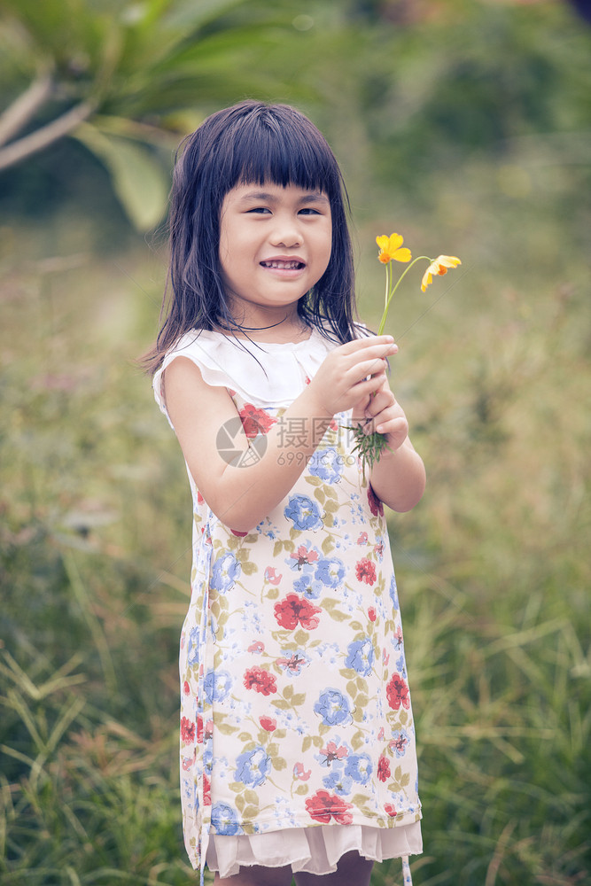 孩子亚洲人可爱女孩的肖像与黄色宇宙花束在手牙般微笑的脸幸福图片