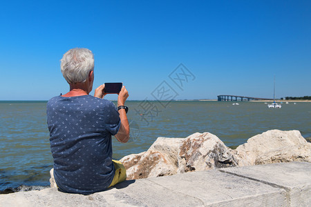 坐在岸边的资深男子从桥到大陆岛IletheRe拍摄照片假期高级的伊莱图片