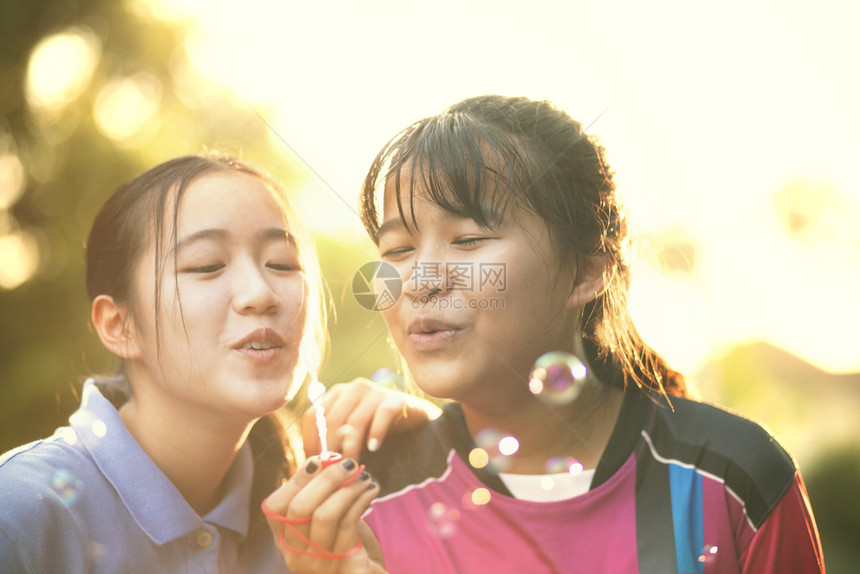 愉快女夏天亚裔青少年的情侣们与美丽的阳光相比用汤泡来放松图片