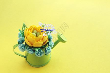作品黄色手工造人花朵有闪光的叶子和许多绿色小水中的纸玫瑰在黄色背景和紫蝴蝶风下可使用小型绿水罐头能够园艺背景图片