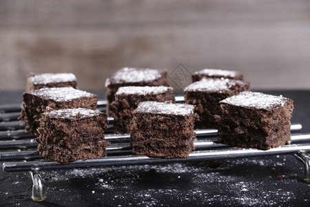湿手棕色底钢网格上巧克力和糖杯蛋糕的正方形块好吃图片