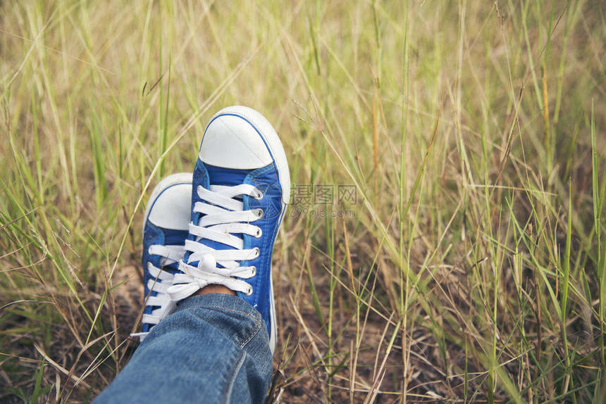 蓝运动鞋漂亮美女穿牛仔裤和蓝色运动鞋在绿草地上自然秋天青少年图片