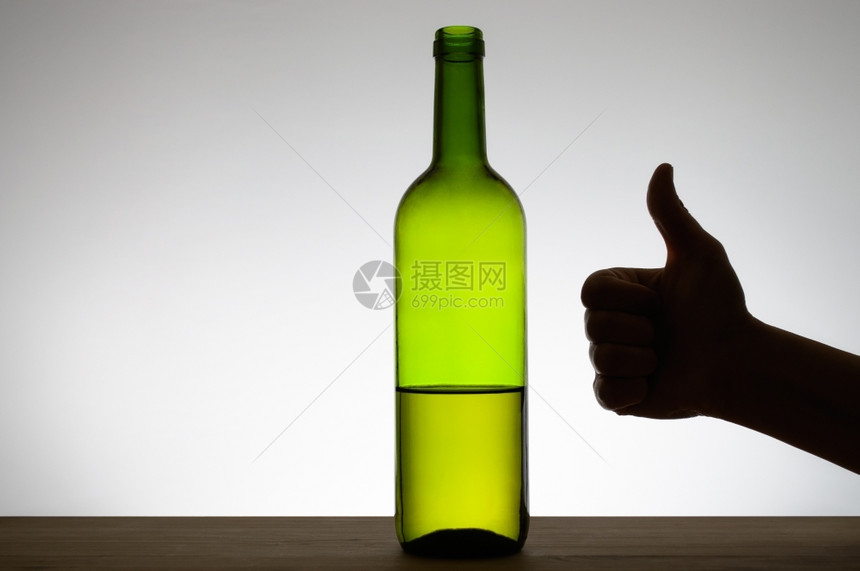 在一瓶红酒旁边举起手势的摇图示意人类成喝图片