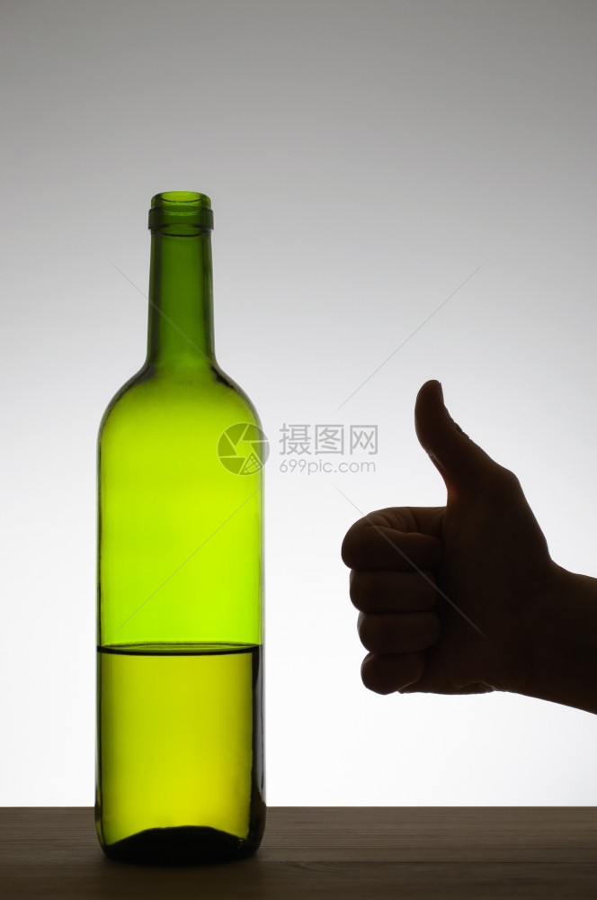工作室女在一瓶红酒旁边举起手势的摇图示意拇指图片