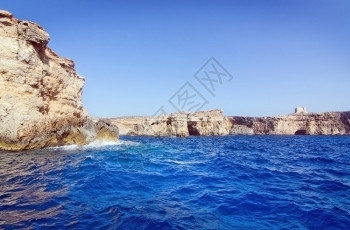 旅行海上阳光在马耳他科米诺岛附近有山洞和蓝地中海洋水的利姆斯通岩石图片