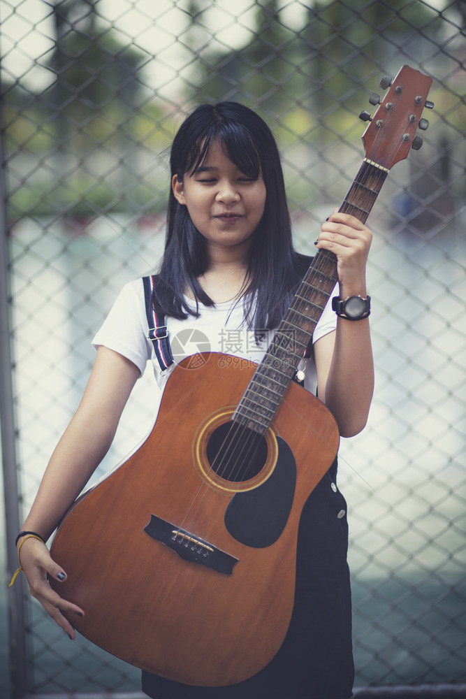 爱好站在户外的亚洲青少年和西班牙语吉他细绳女孩图片
