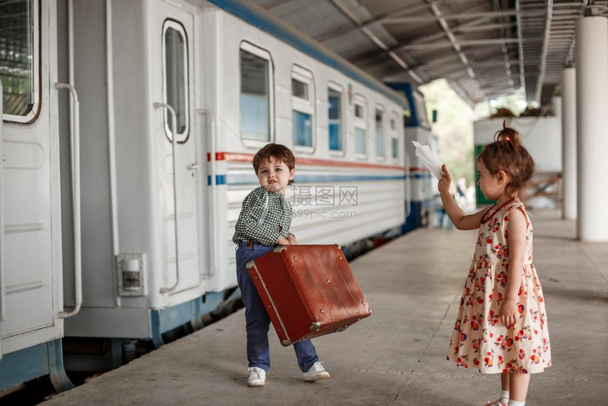 相机身体在小火车站穿着旧衣服和式手提箱的男女小孩和少旅游图片