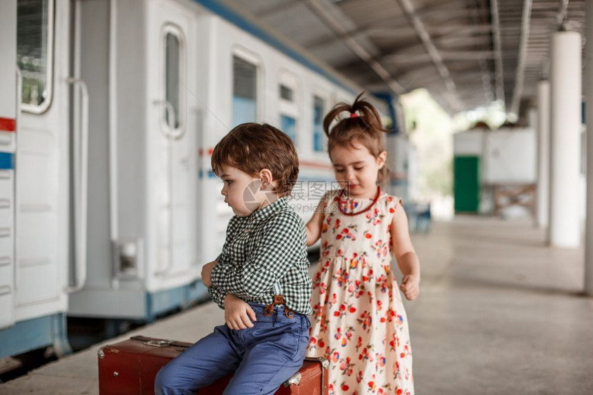 在小火车站穿着旧衣服和式手提箱的男女小孩和少子美丽图片