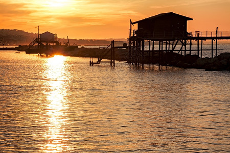 自然风景日落时海上的高跷屋阳光反射在水面上日落时海的高跷屋安科纳图片