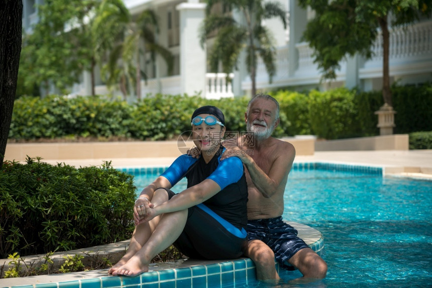 假期老年夫妇在游泳池共中放松浪漫的户外图片