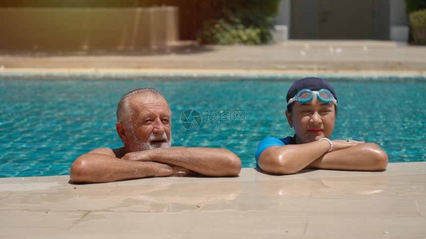 老年夫妇在游泳池共中放松假期积极的乐趣图片