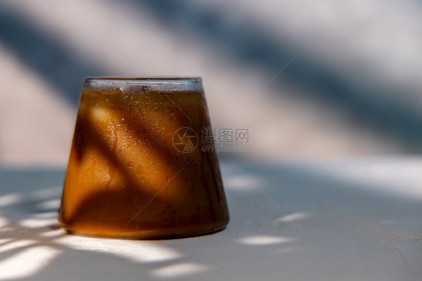 摇天拿铁a在炎热夏日的冰咖啡冷饮料杯中阳光照耀在墙上图片