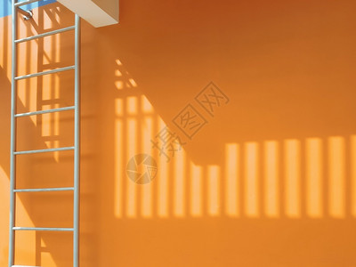 橙色建筑墙外的防火逃生处表面的薄膜阳光和遮明亮的紧急情况逃脱图片