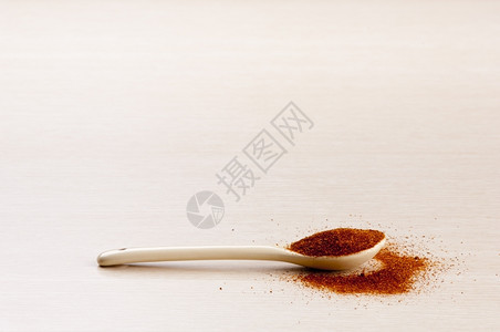 红辣椒在勺子里有几块洒在木制背景上复香料晒干图片