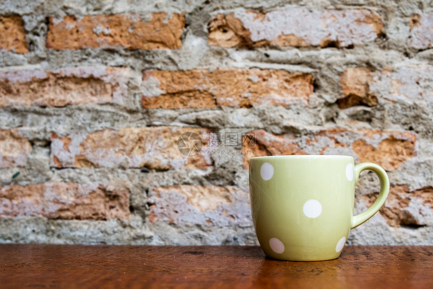 优质的用旧砖墙在木地板上涂绿色咖啡杯子白的图片