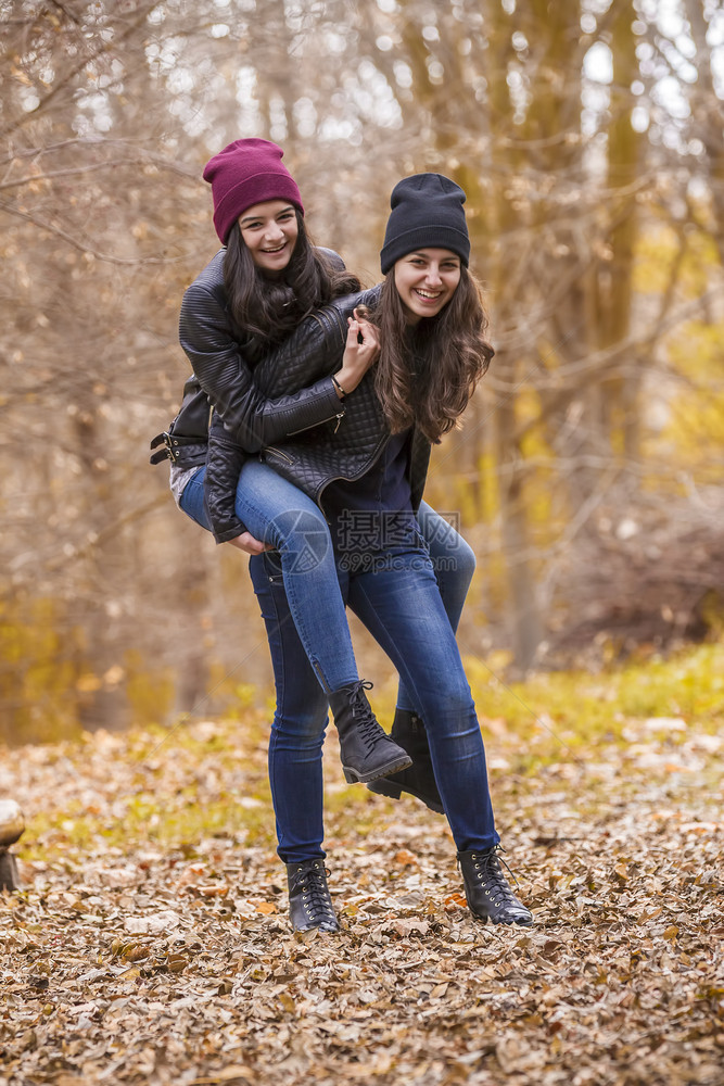 树叶人们朋友两个笑的女孩在秋天公园户外玩图片