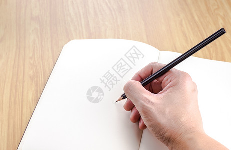 手握黑铅笔在木材板商业模上的空白开笔记本上写字书面签名纸图片