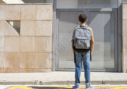 吸引人的带着他背包好孩子站在学校门口着青少年轻的图片